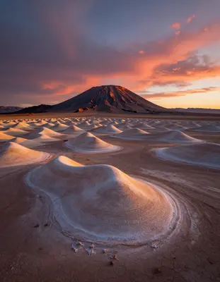 The Atacama desert at dusk transforms into a surreal alien landscape with undulating dunes of iridescent salt and minerals, a