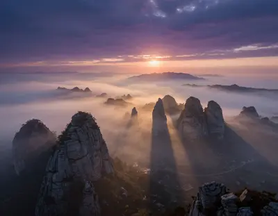 A cinematic vision of the Karst plateau shrouded in a mystical fog that gently rises from the valleys, with towering limeston