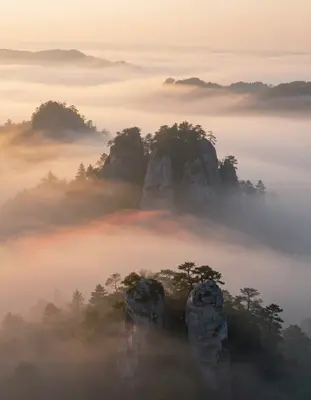 A dreamy, ethereal landscape of the Karst plateau shrouded in a thick, misty fog that softly glows with a warm, golden light,