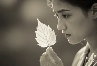 A head-and-shoulders portrait of a young botanist with an intense gaze, holding a delicate leaf close to her face, her featur