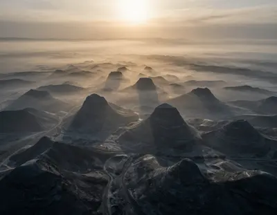 The Karst plateau shrouded in a mystical fog at golden hour, with monochrome hues of grey and blue dominating the landscape, 