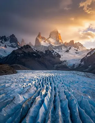 Patagonian glaciers sprawl across a vast, surreal landscape under the warm, golden light of a setting sun, with towering sera